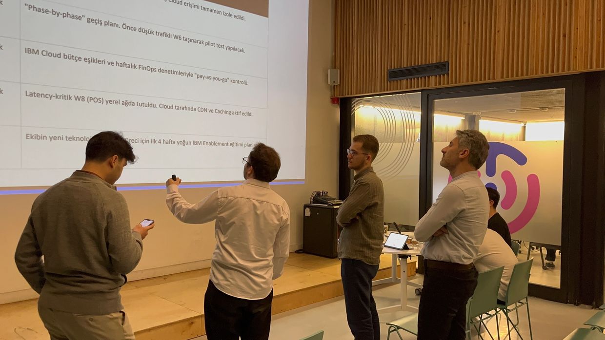 A group of men attentively watching a presentation on a wall projector in a modern office.