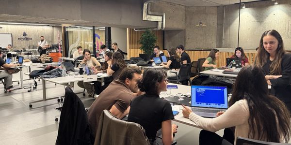 People collaborating in a modern coworking space with laptops and discussions.