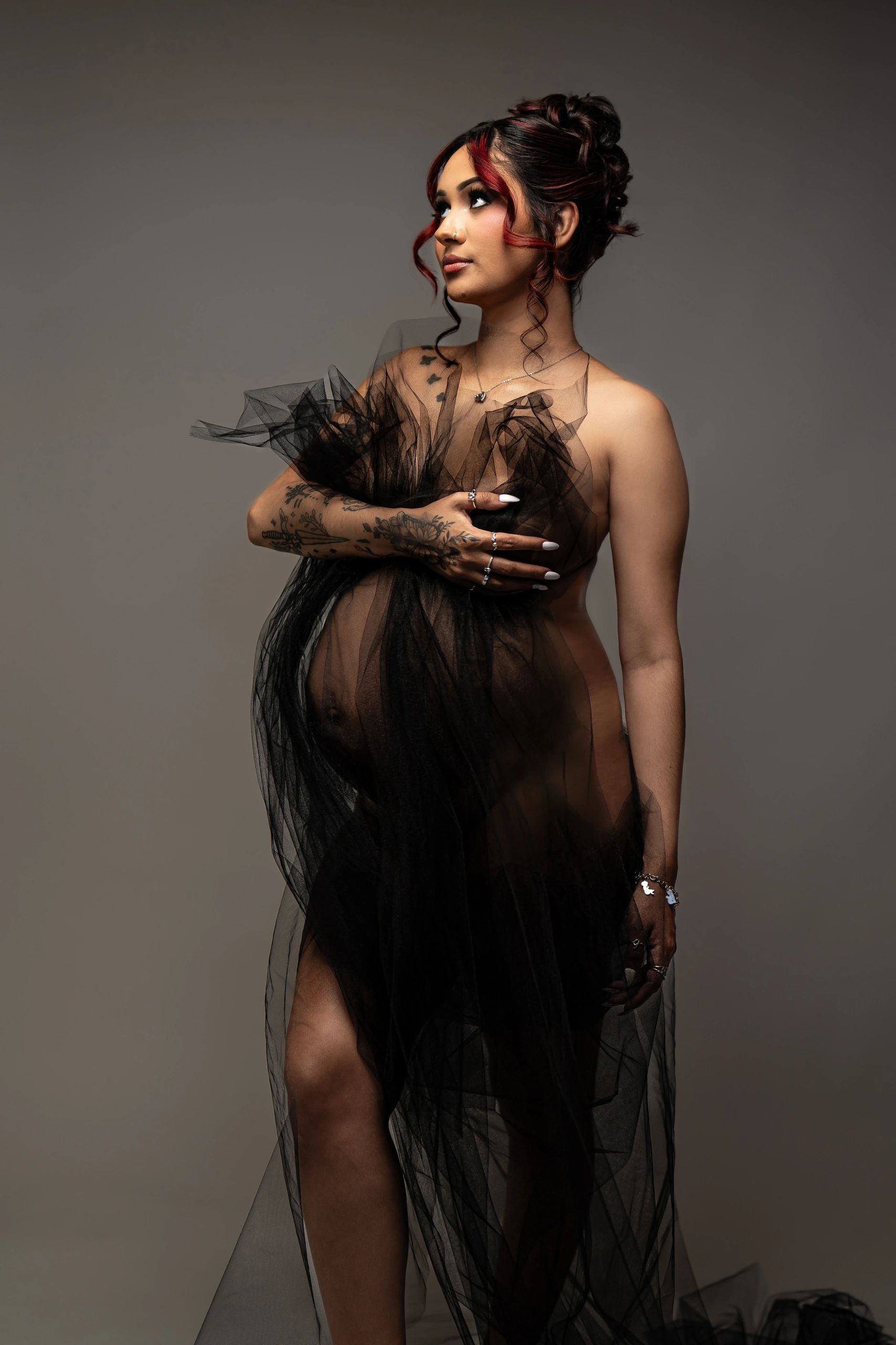 Pregnant woman wrapped in black tulle fabric.