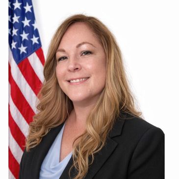 Professional woman smiling in front of an American flag.