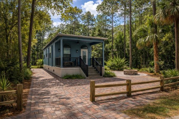 Small blue cabin in a wooded area.