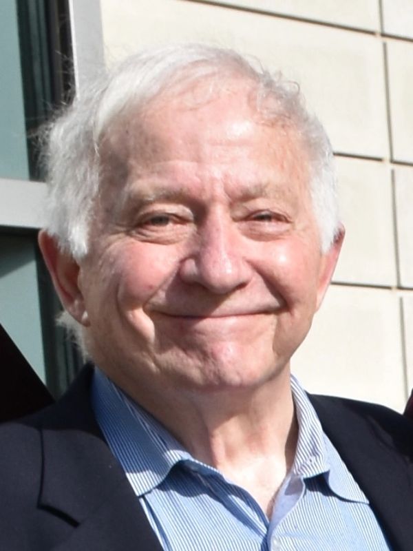 Elderly man smiling warmly outdoors.