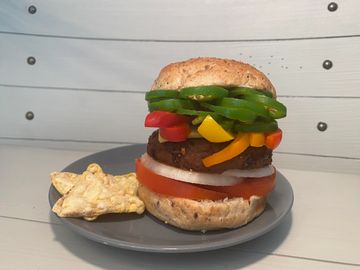 Plant-based patty, jalapeños, cheese, onions, bell peppers, tomato, special sauce on a bun.