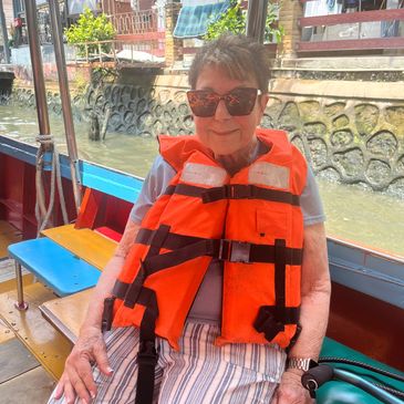 Older woman wearing sunglasses and an orange life jacket on a boat.
