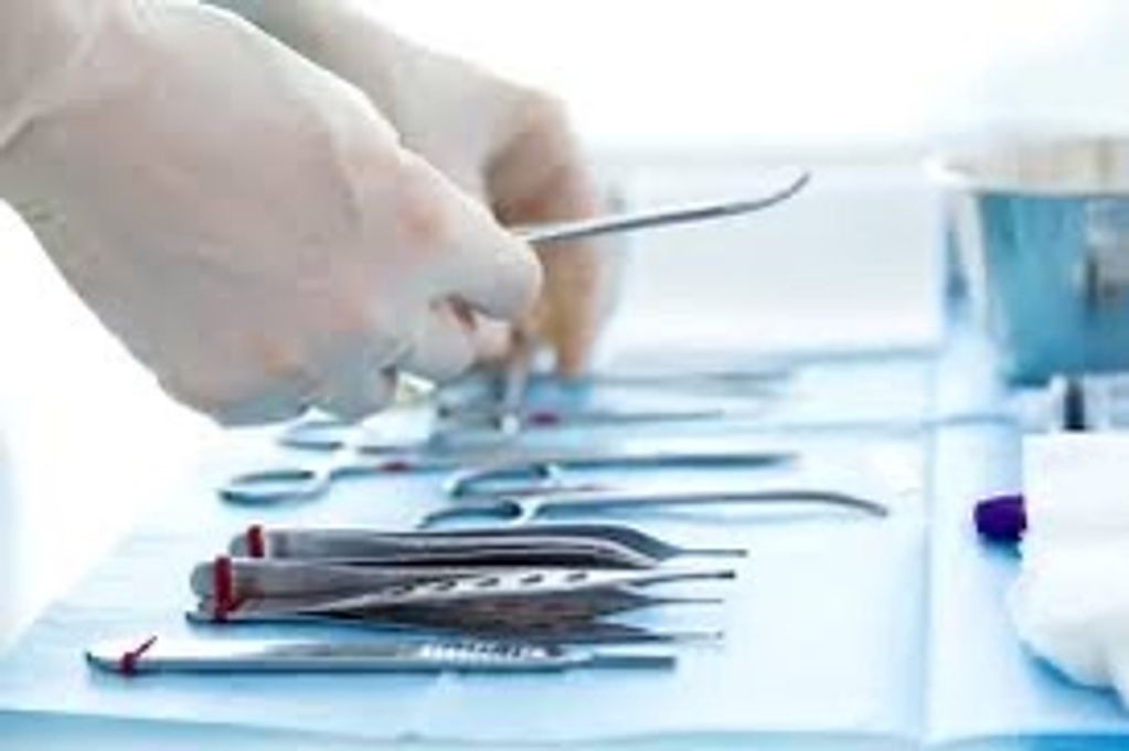 Hands arranging surgical tools on a sterile blue cloth.