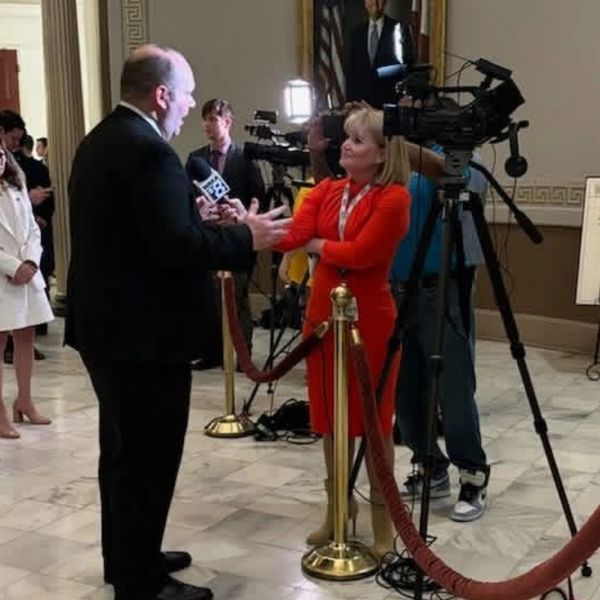 Reporter interviews a man in a formal setting.