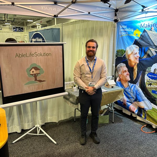 Man standing at a booth with AbleLifeSolution sign at an event.