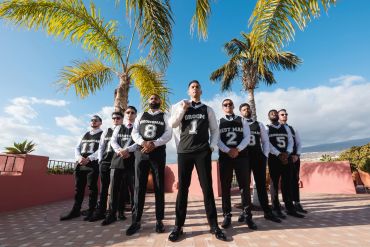 Group of men posing outdoors in matching outfits.