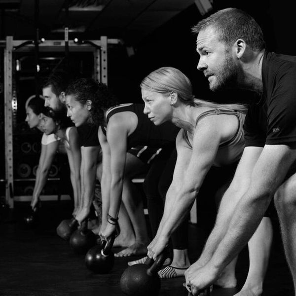 Group of people exercising with kettlebells in a gym, focused and determined.