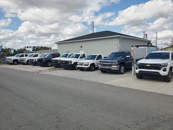 A lineup of various Chevrolet trucks and SUVs parked beside a building under a cloudy sky.