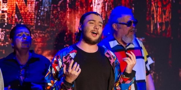 Artista cantando com expressão emotiva no palco.