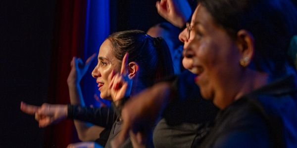 Grupo de mulheres expressando emoção em palco.
