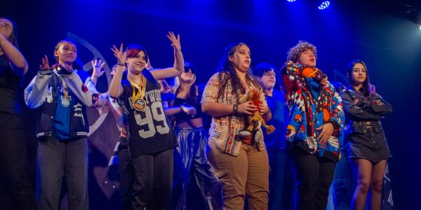 Grupo de jovens no palco com iluminação azul.