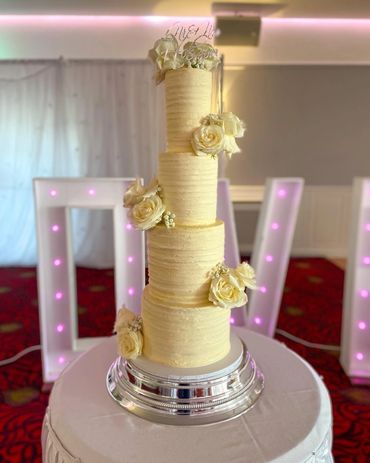 4 tier wedding cake with textured buttercream and decorated with roses.