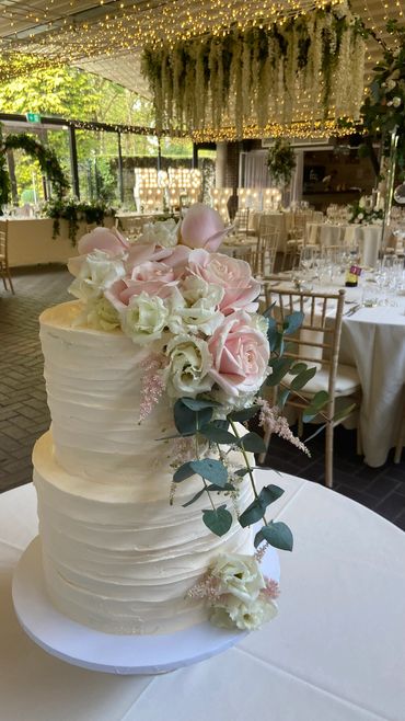 Two tier buttercream wedding cake with pink and white florals.
