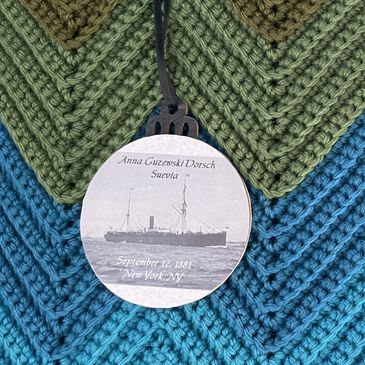 Round tag with ship image and text on crocheted fabric background.