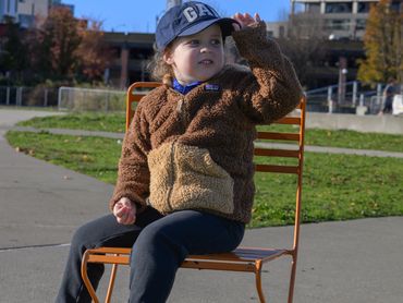 Child sitting on an orange chair with the Space Needle in the background.