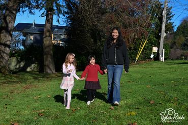 Three females holding hands and walking outdoors on a sunny day.