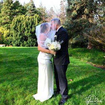 Bride and groom sharing a kiss under the veil in a garden.
