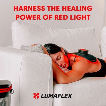 Woman relaxing on couch using a red light therapy device on her back.