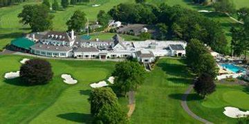A golf clubhouse surrounded by green fairways and sand bunkers.
