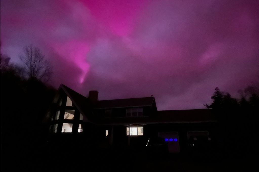 House silhouette under a vibrant purple sky at night.