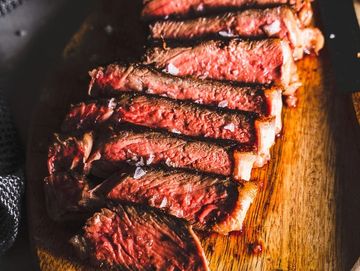 Juicy sliced steak cooked to medium-rare on a wooden board.