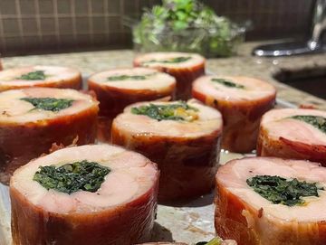 Sliced chicken rolls stuffed with spinach on a kitchen counter.