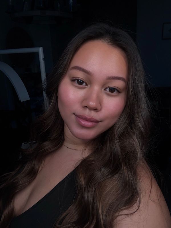 Close-up portrait of a young woman with long wavy hair and natural makeup.