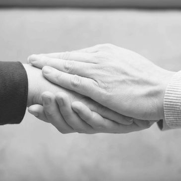 Two hands from one person rest top and bottom around another person's hand