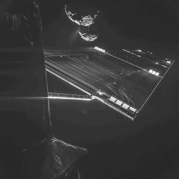 A spacecraft solar array extends in front of a two-lobed comet