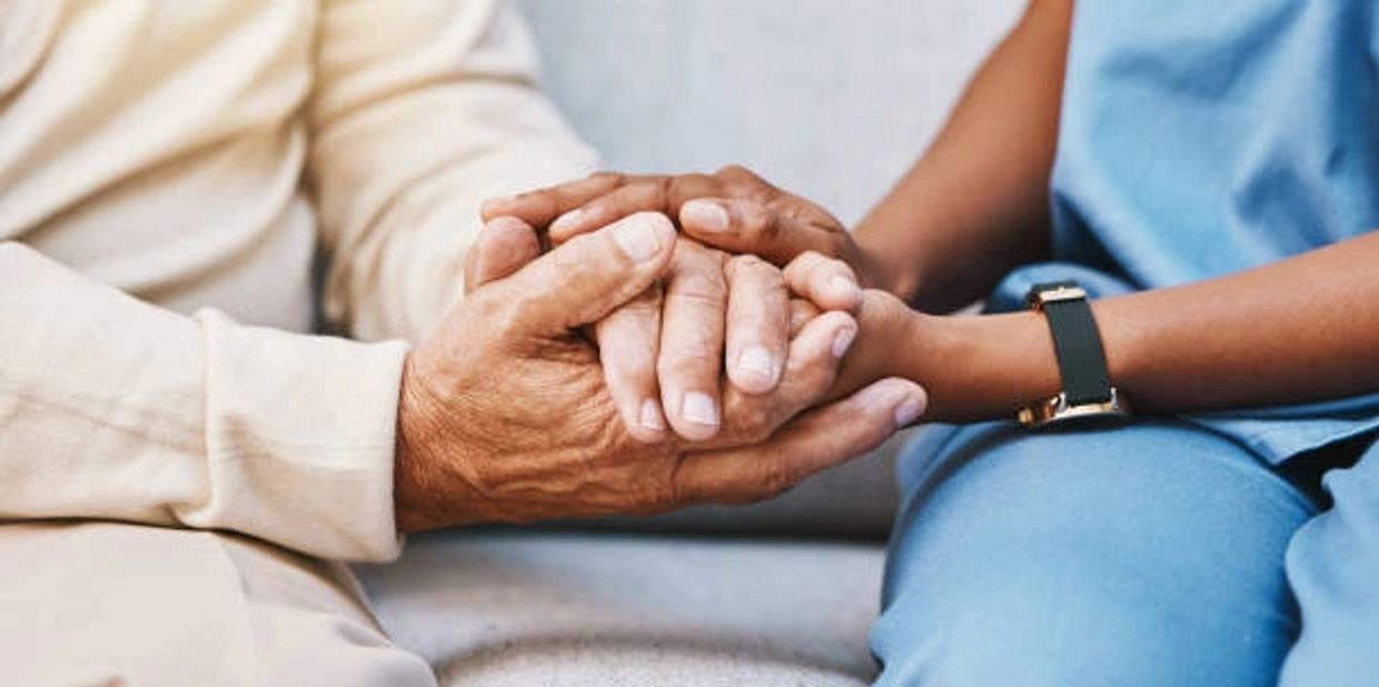 Two people holding hands, showing support and care.