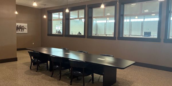 Empty conference room with a long table and black chairs.