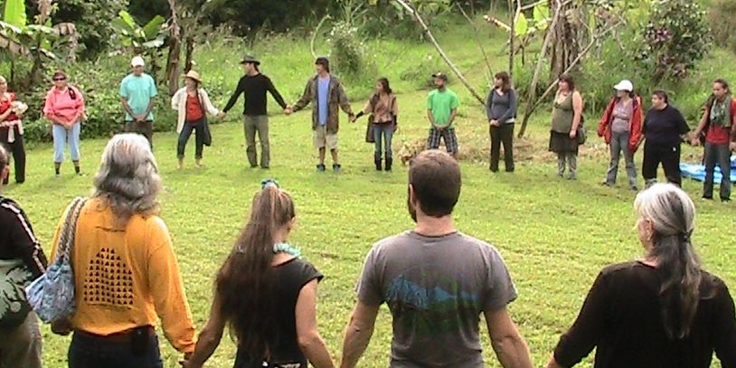 Group of people holding hands in a circle outdoors.