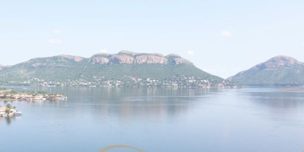 Scenic view of mountains reflecting on calm lake water under clear sky.