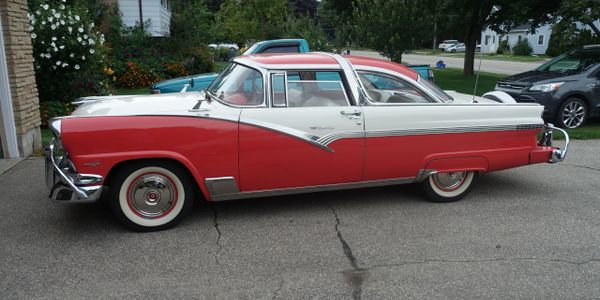Classic red and white vintage car parked on a driveway.
