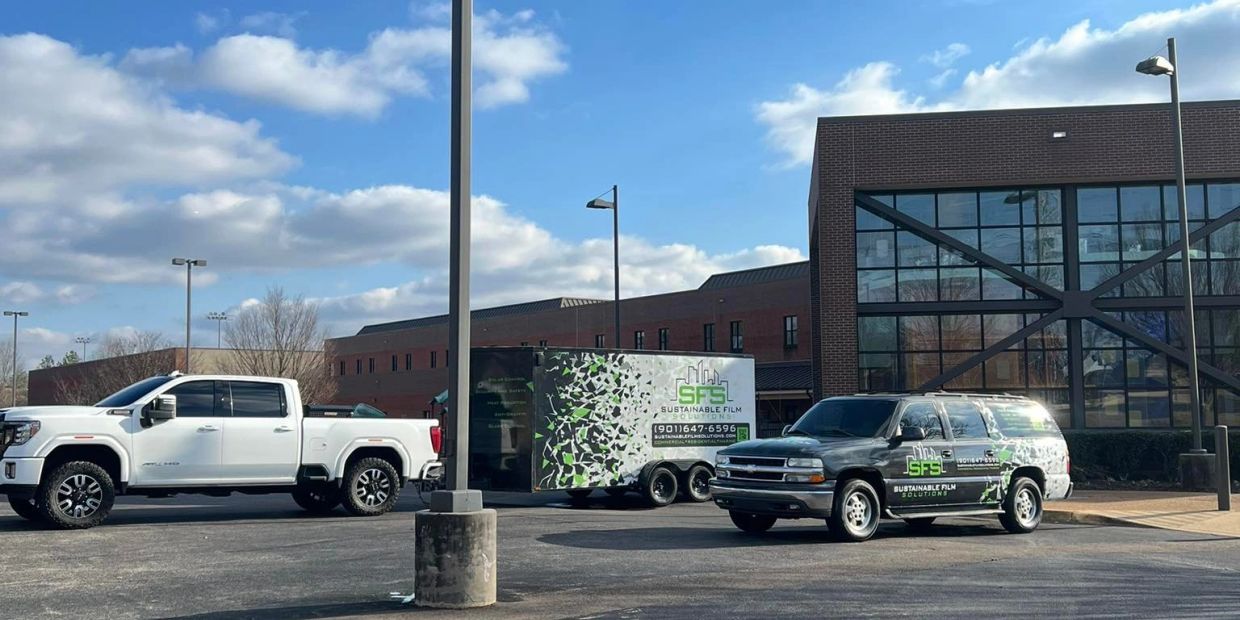 White truck and black SUV with Sustainable Film Solutions branding.