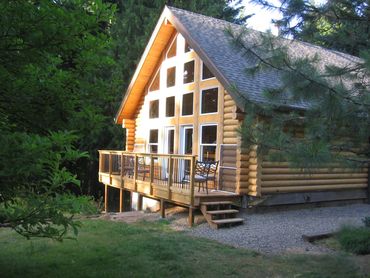 Elevated cedar deck off of main living space of log home featuring stairway and epoxy-coated railing