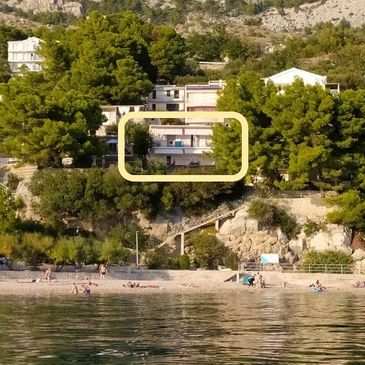 Beachfront houses nestled among trees on a rocky hillside.