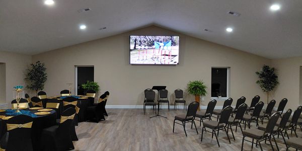 Event space with chairs, tables, and a large screen.