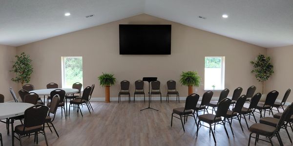 Empty meeting room with chairs, tables, and TV.