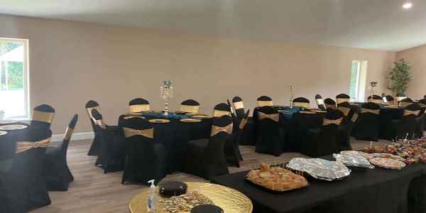 Event room with black and gold decorations and buffet setup.
