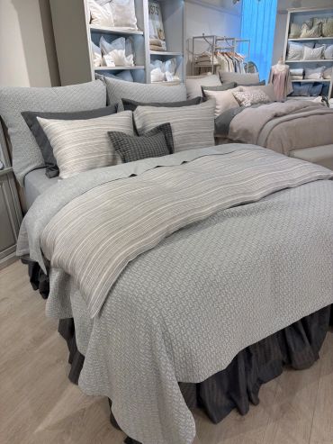 Cozy bed with layered neutral-toned bedding and decorative pillows in a stylish bedroom.