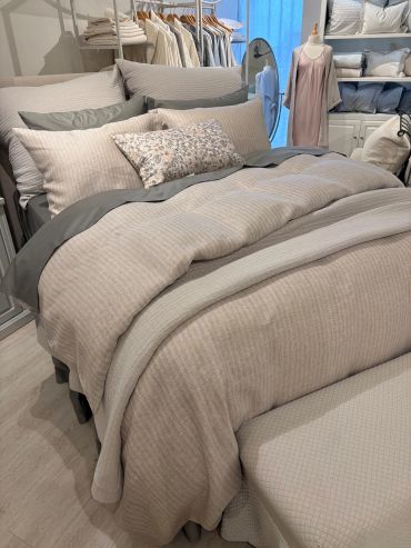 Cozy beige and gray bed setup with floral accent pillow in a stylish bedroom.