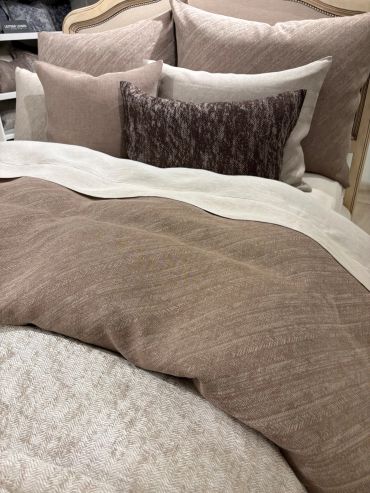 Elegant bed with layered neutral-toned bedding and textured pillows.