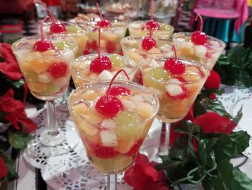 Elegant fruit cocktail desserts garnished with cherries in clear glasses.
