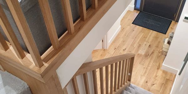 Wooden staircase leading down to a front door with hardwood flooring.