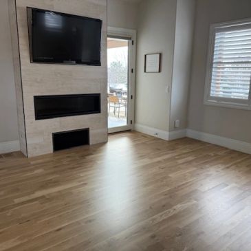 Minimalist living room with wooden floor and mounted TV.
