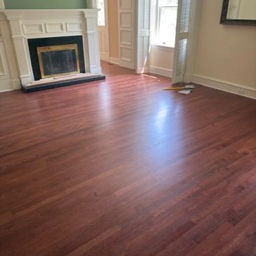 Empty room with wooden floor and fireplace.