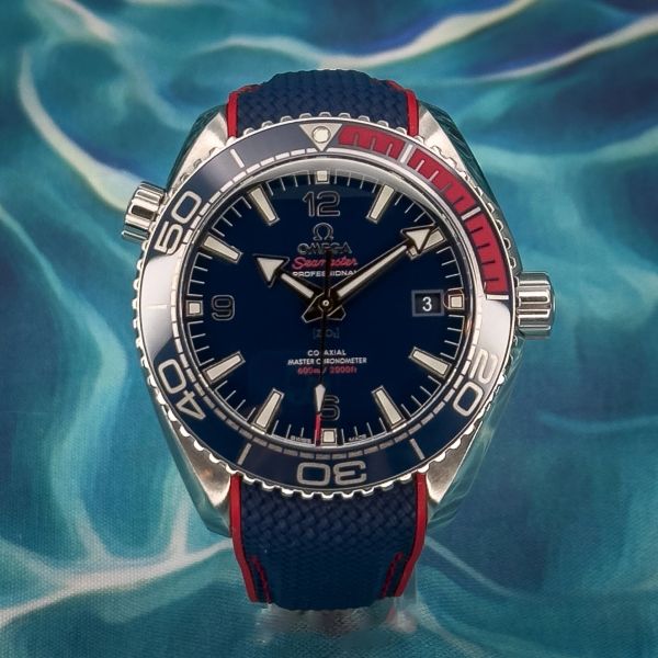 Omega Seamaster dive watch with blue and red accents on a textured strap.